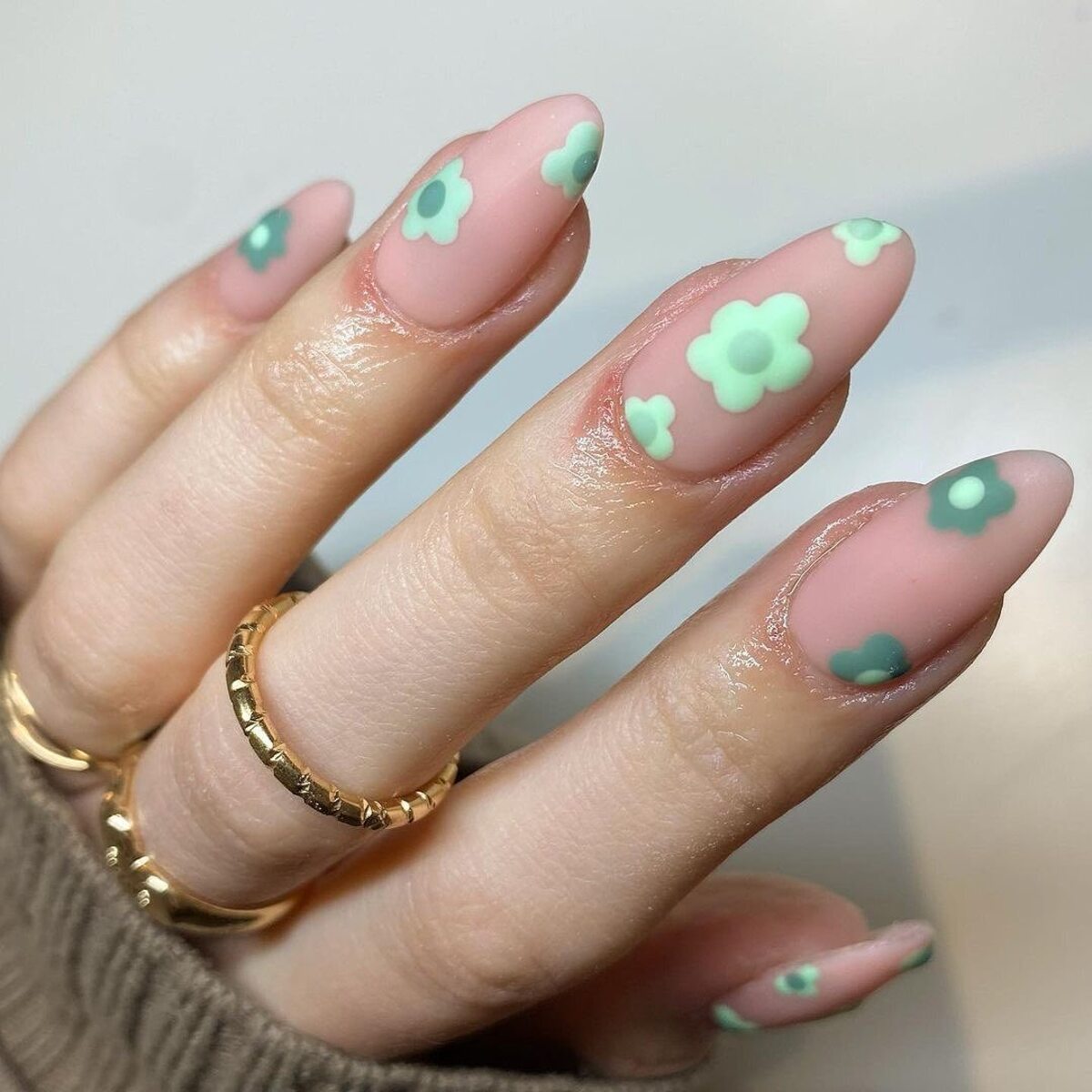 20. Playful Matte Nude Nails with Sage Green Floral Accents