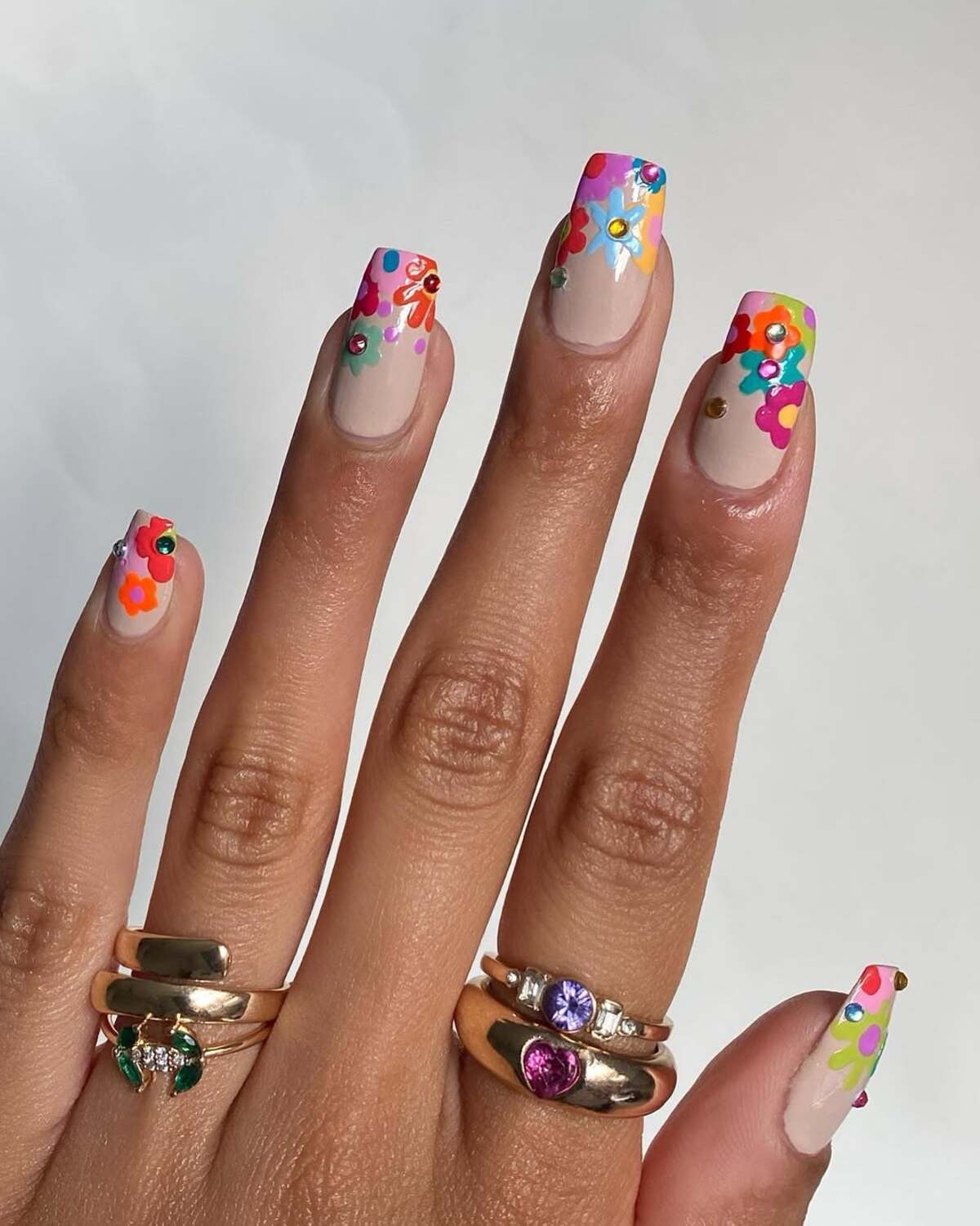 24. Bold Floral French Tips with Rhinestone Embellishments