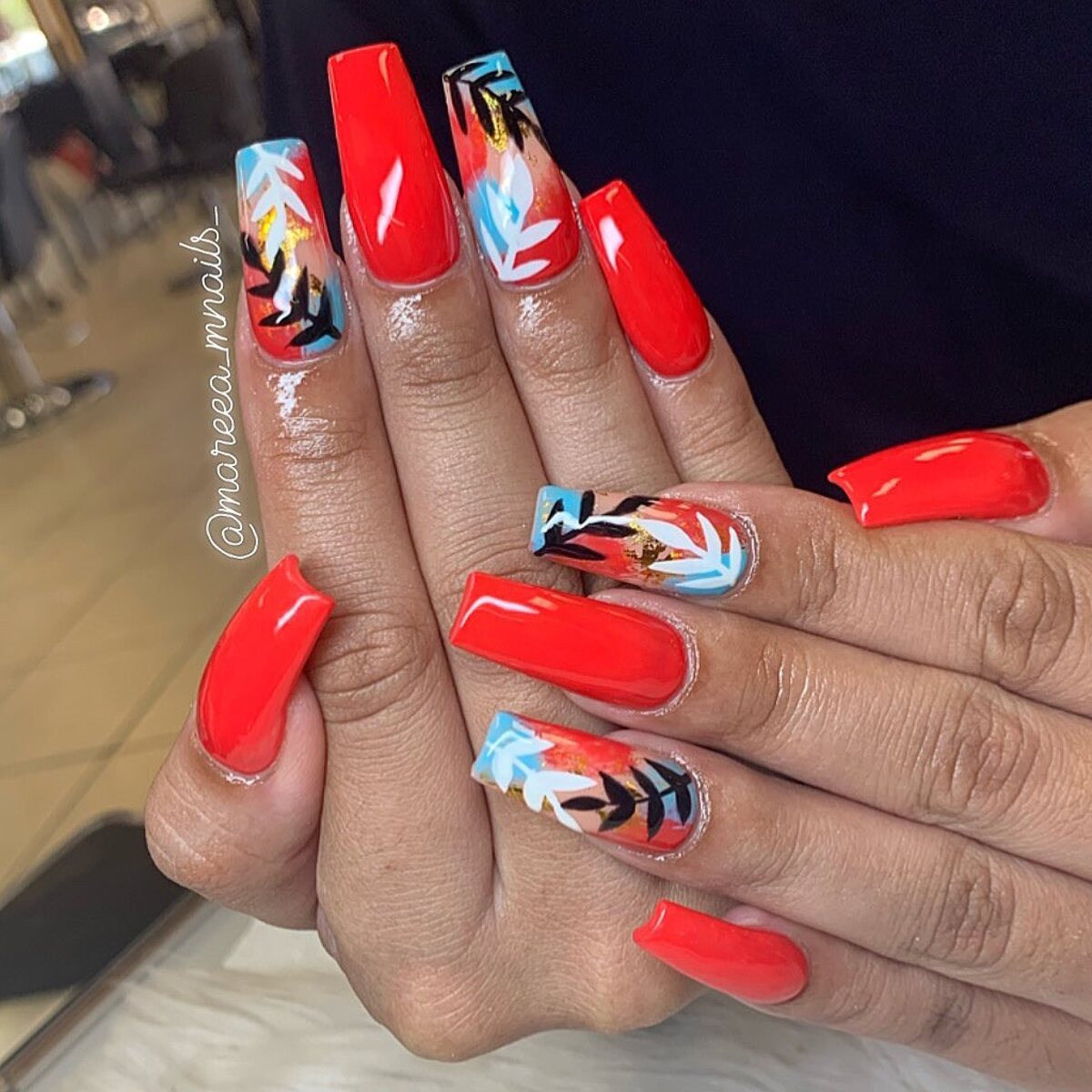 14. Bold Coral Coffin Nails with Tropical Leaf Accents